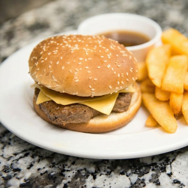 Cheeseburger with a sesame seed bun, a side of fries, and a small cup of gravy.